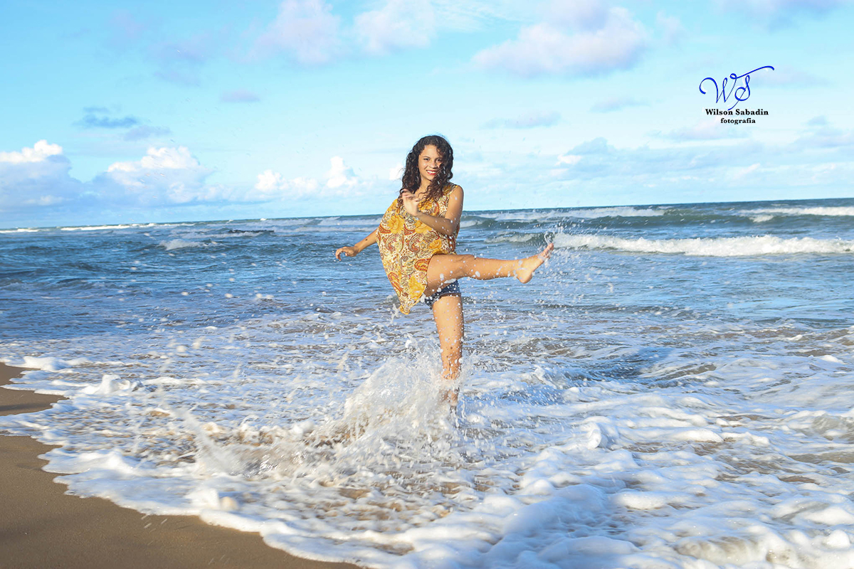 fotografia de 15 anos a debutante chutando as ondas