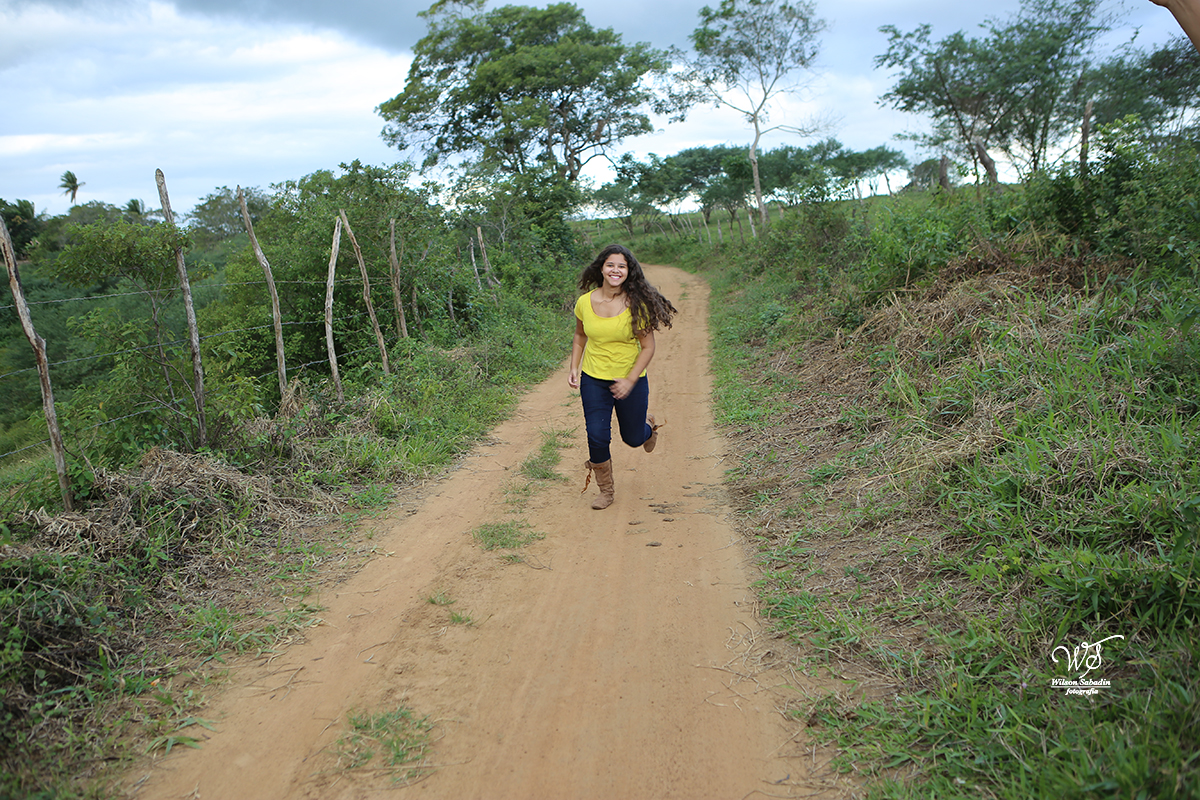 fotografia de 15 a debutante correndo na estrada de barro