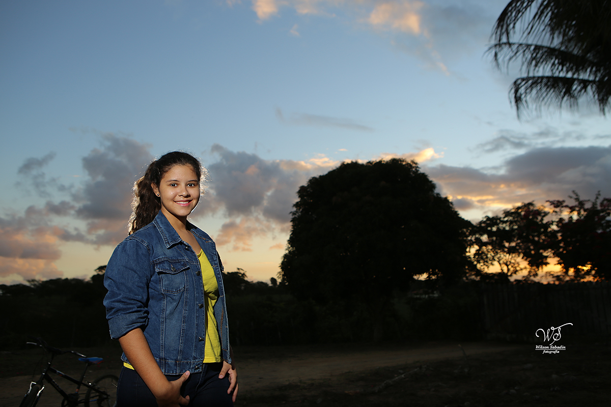 fotografia de 15 a debutante ao lado de uma grande árvore