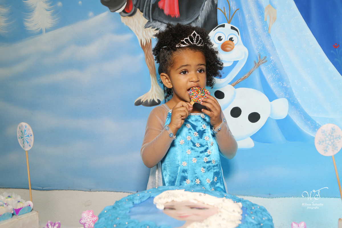 festa infantil a aniversariante enfrente ao painel da frozen