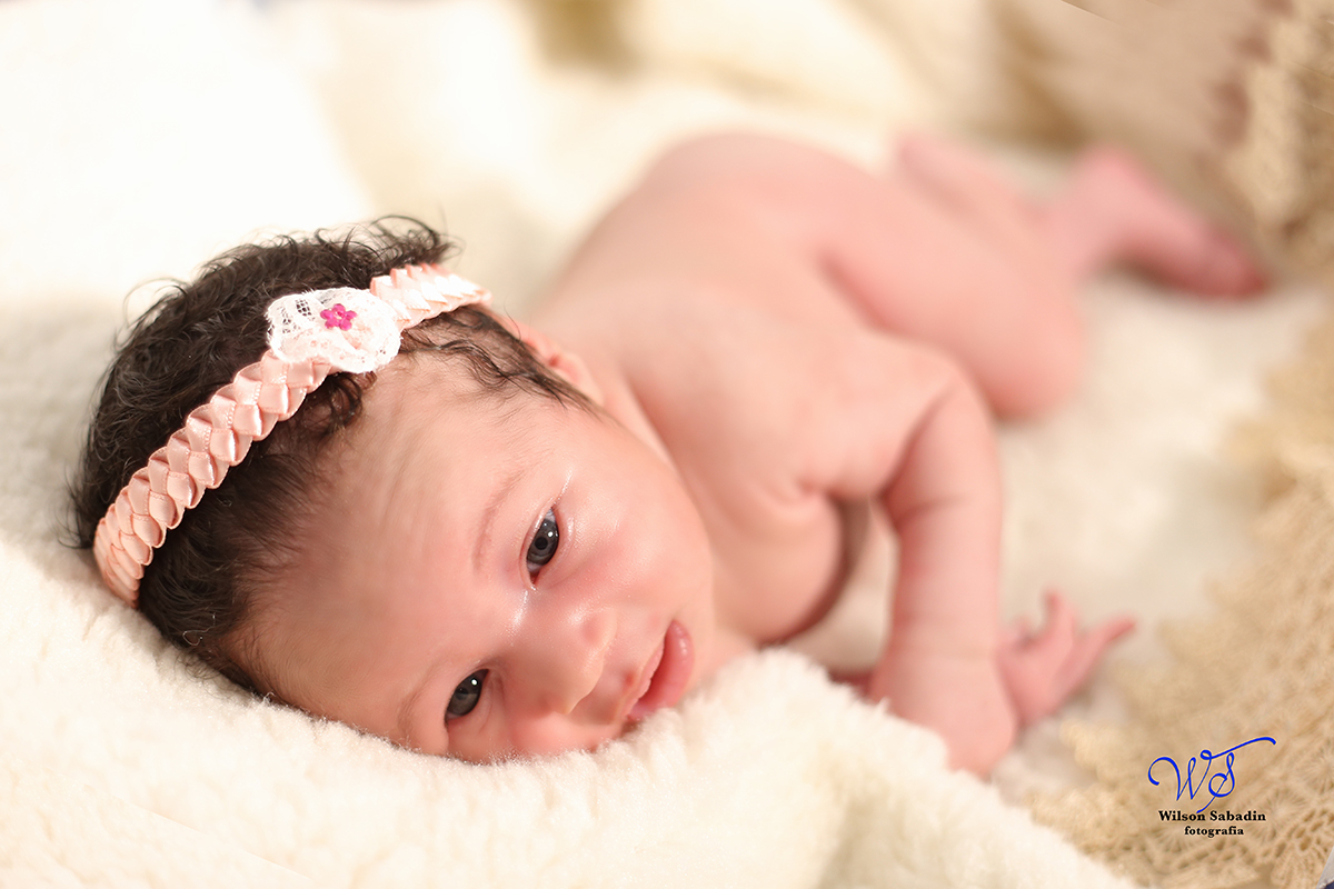 Fotografia de newborn em Salvador, o bebe com laço cor de rosa na cabeça