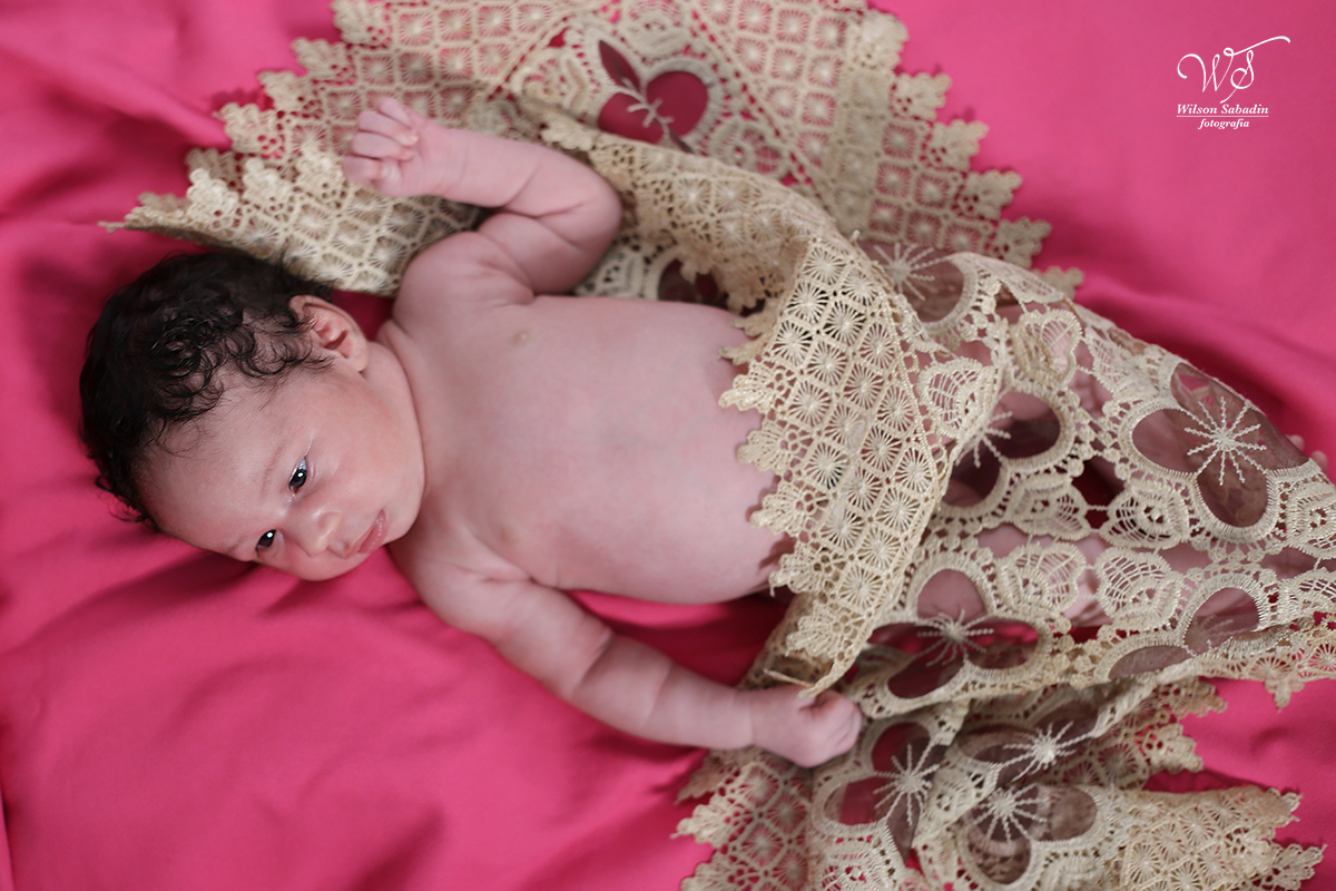 Fotografia de newborn em Salvador, o bebe sob tecido rosa