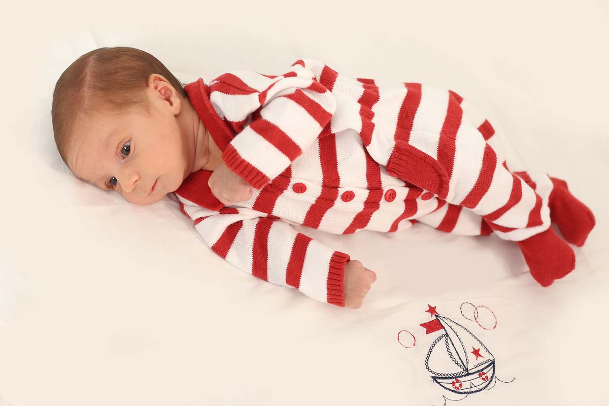 Fotografia de newborn em Salvador, o bebe com macacão vermelho e branco