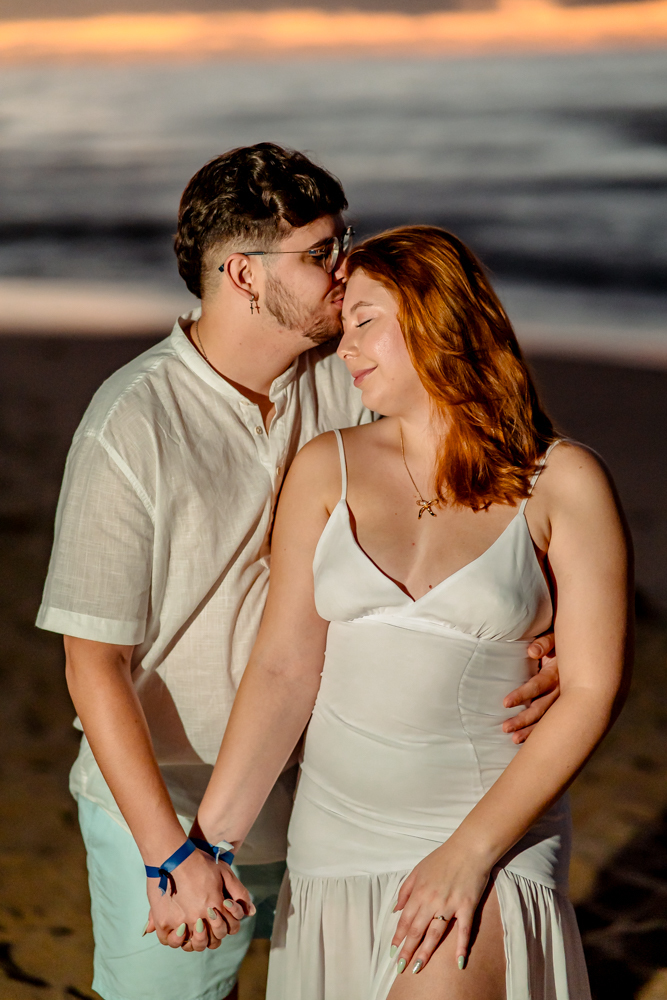 aloma e Pablo vivendo a leveza do amor na areia dourada de Imbassaí, com a luz suave do amanhecer como cenário.