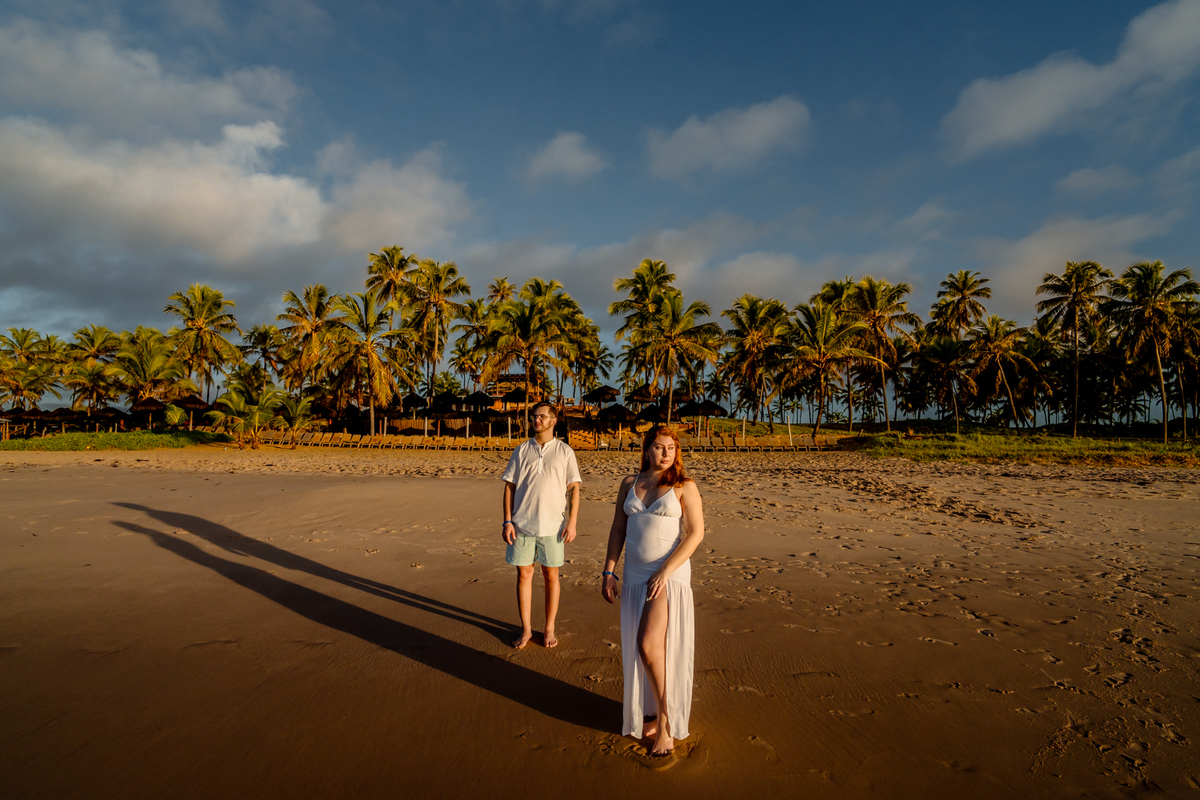 aloma e Pablo vivendo a leveza do amor na areia dourada de Imbassaí, com a luz suave do amanhecer como cenário.