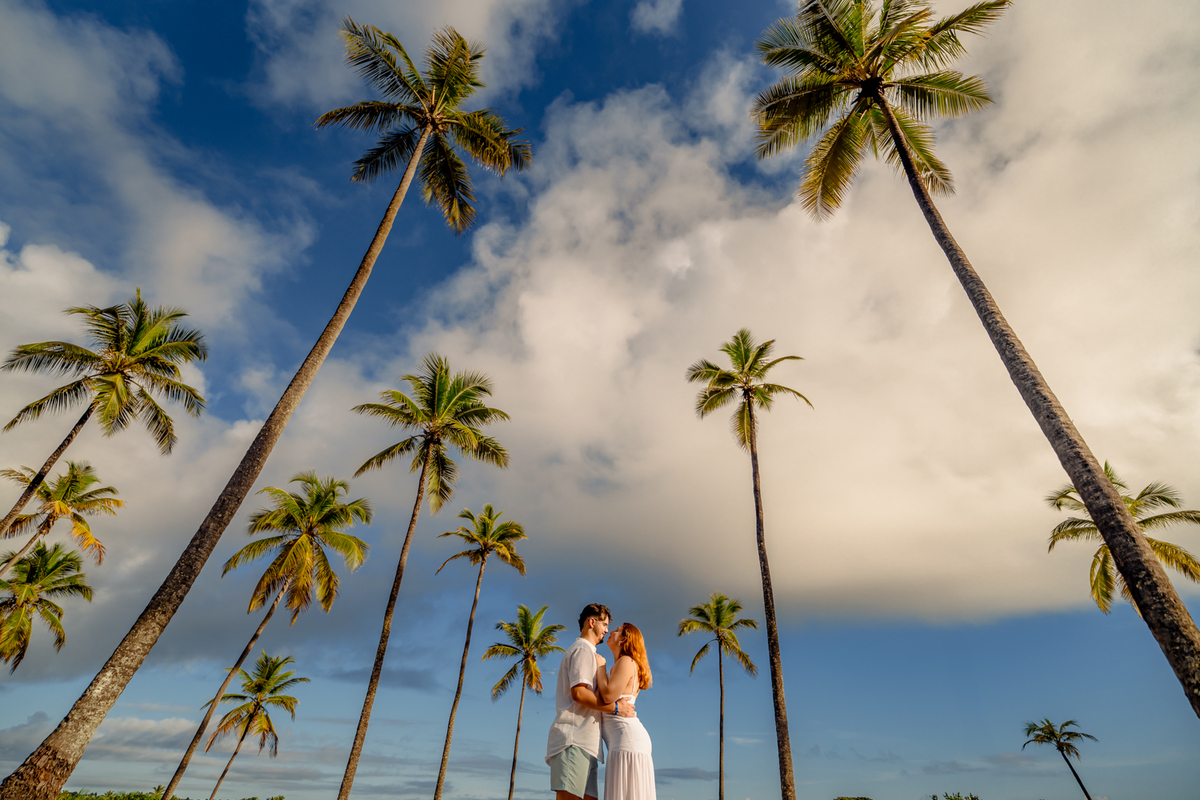 aloma e Pablo vivendo a leveza do amor na areia dourada de Imbassaí, com a luz suave do amanhecer como cenário.