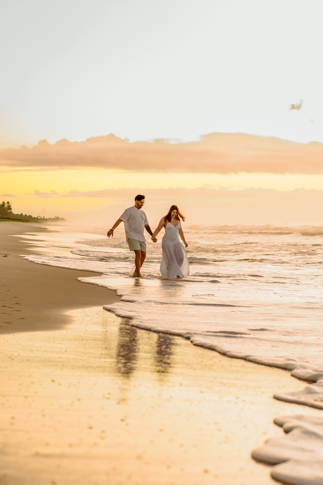 aloma e Pablo vivendo a leveza do amor na areia dourada de Imbassaí, com a luz suave do amanhecer como cenário.