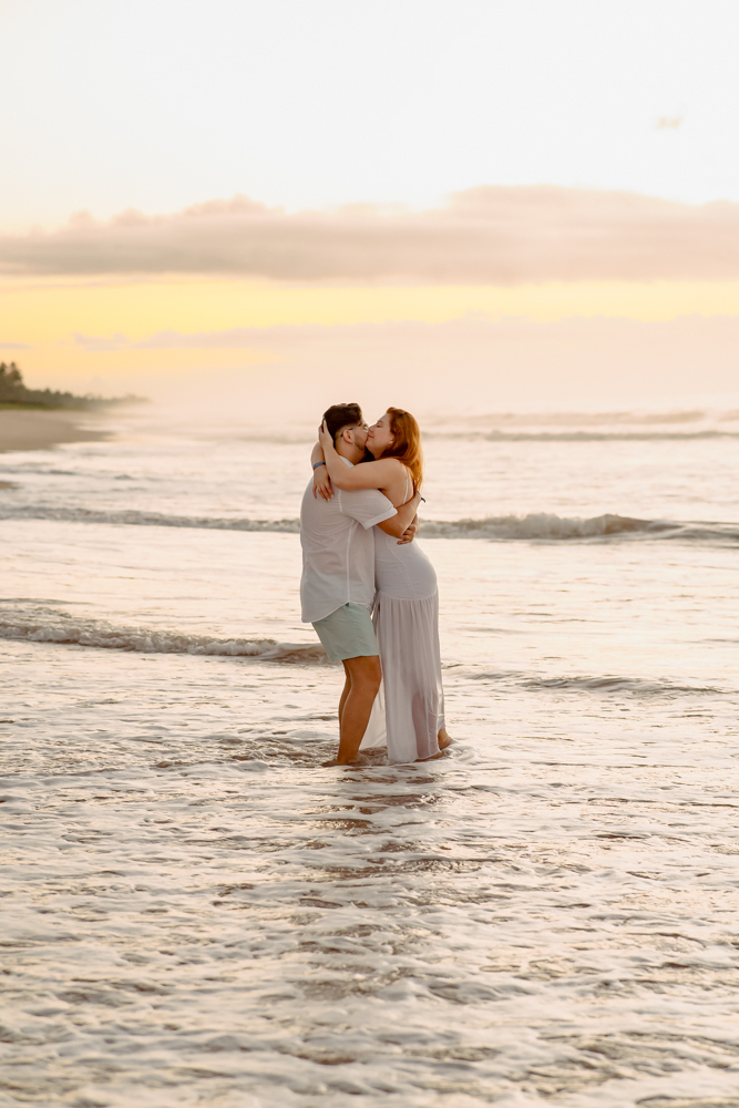 aloma e Pablo vivendo a leveza do amor na areia dourada de Imbassaí, com a luz suave do amanhecer como cenário.