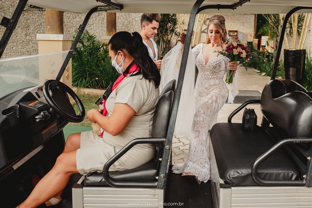 Noiva no carrinho de golf indo para cerimonia ao ar livre em frente ao mar e no por do sol