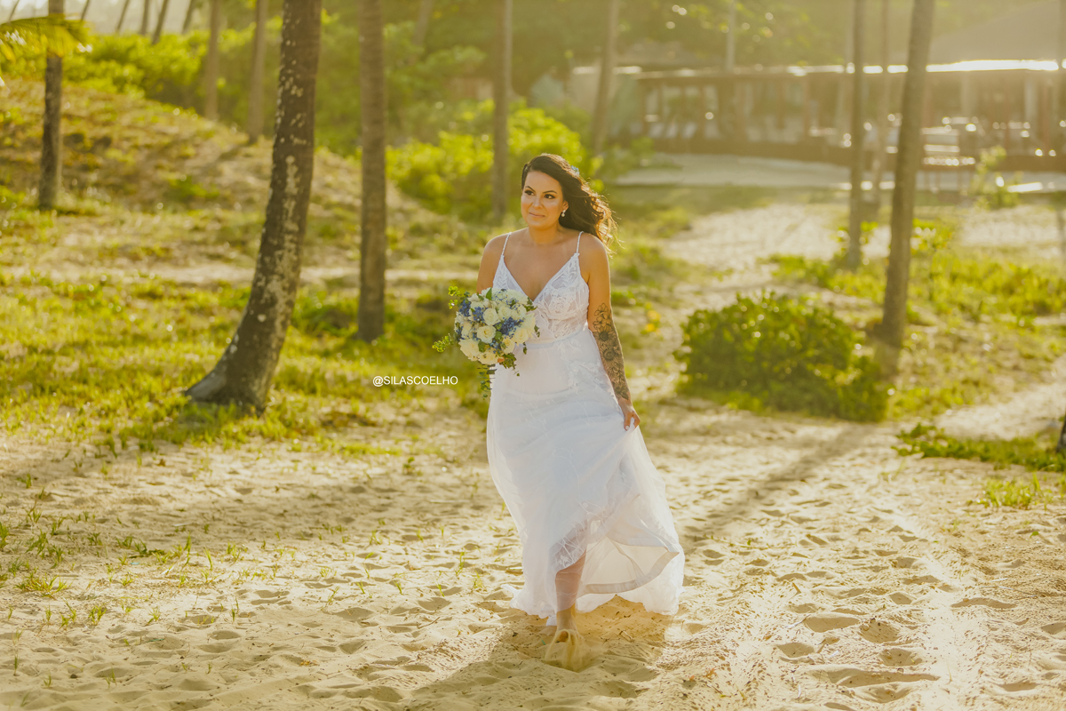 Noiva subindo a duna entrando no casamento com pé na areia e no pôr do sol