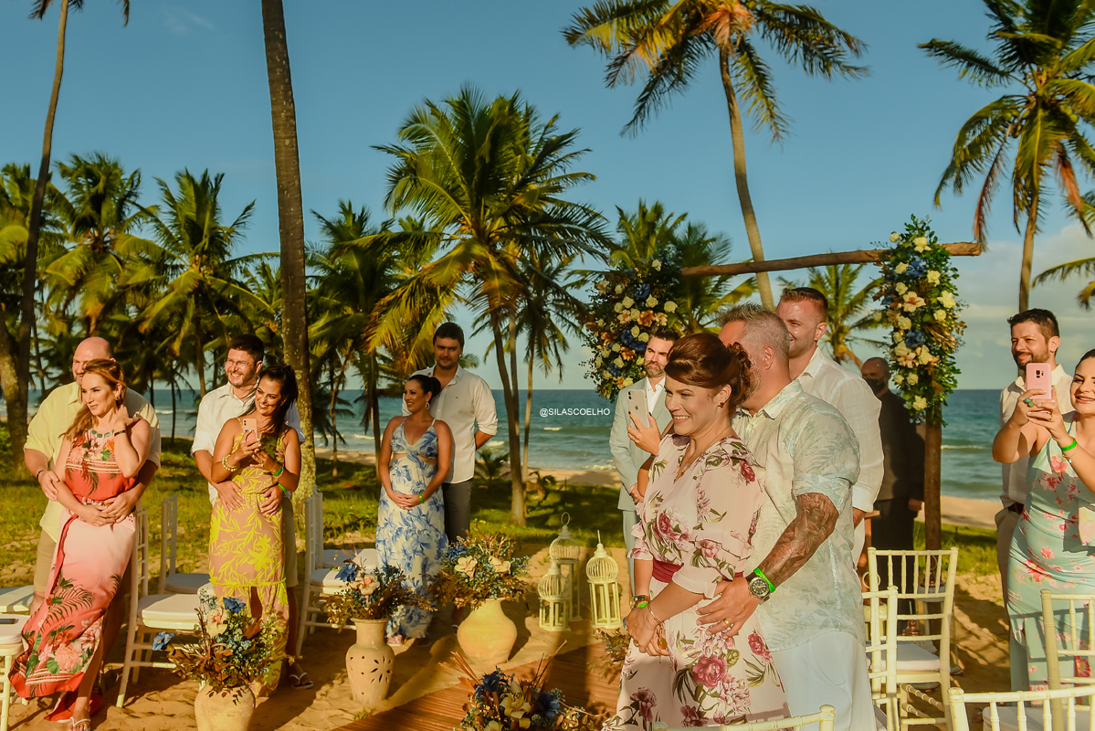 noivo e convidados vendo a noiva entrar no casamento na praia frente ao mar na bahia