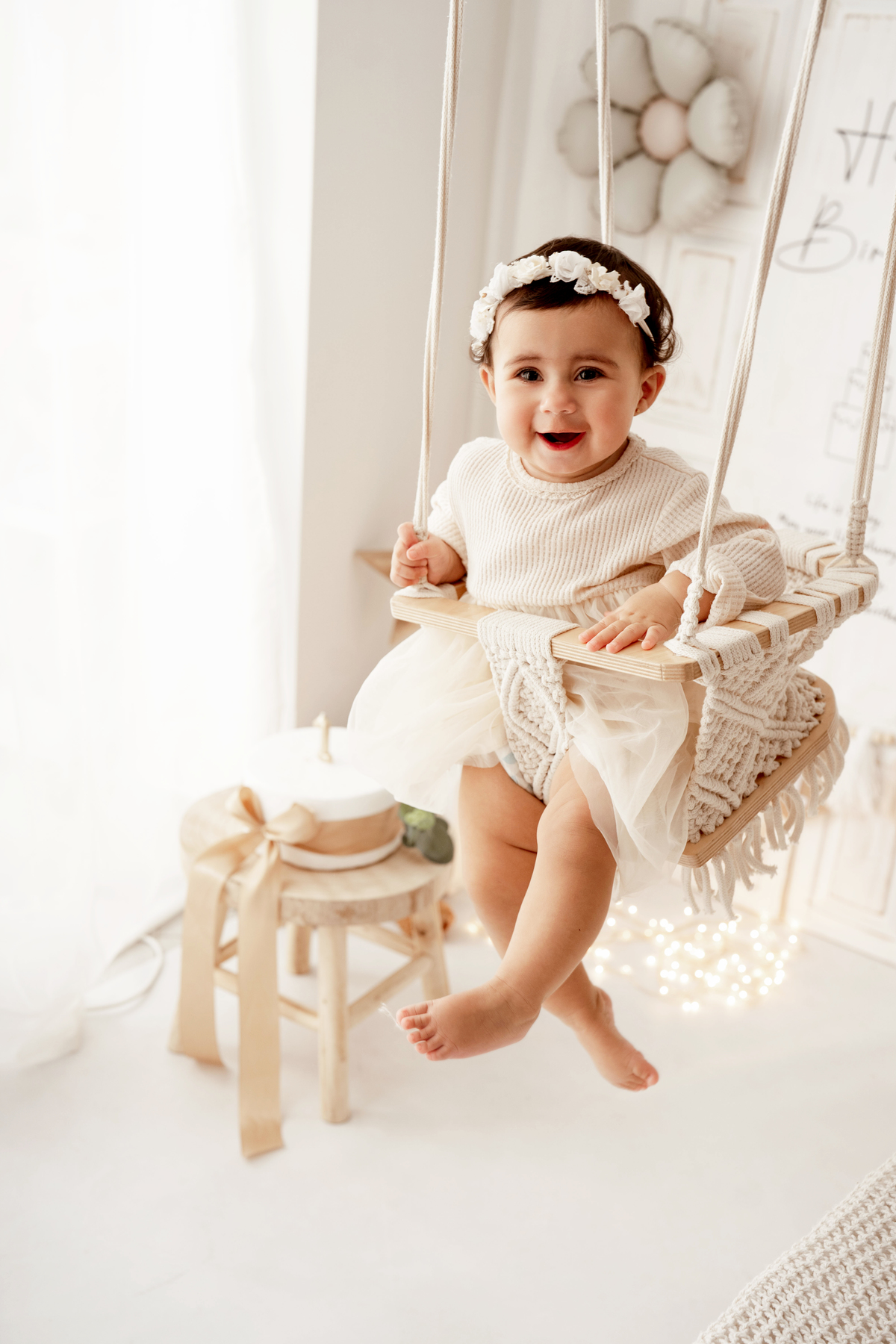 Fotografia de bebé em baloiço com vestido em tons neutros