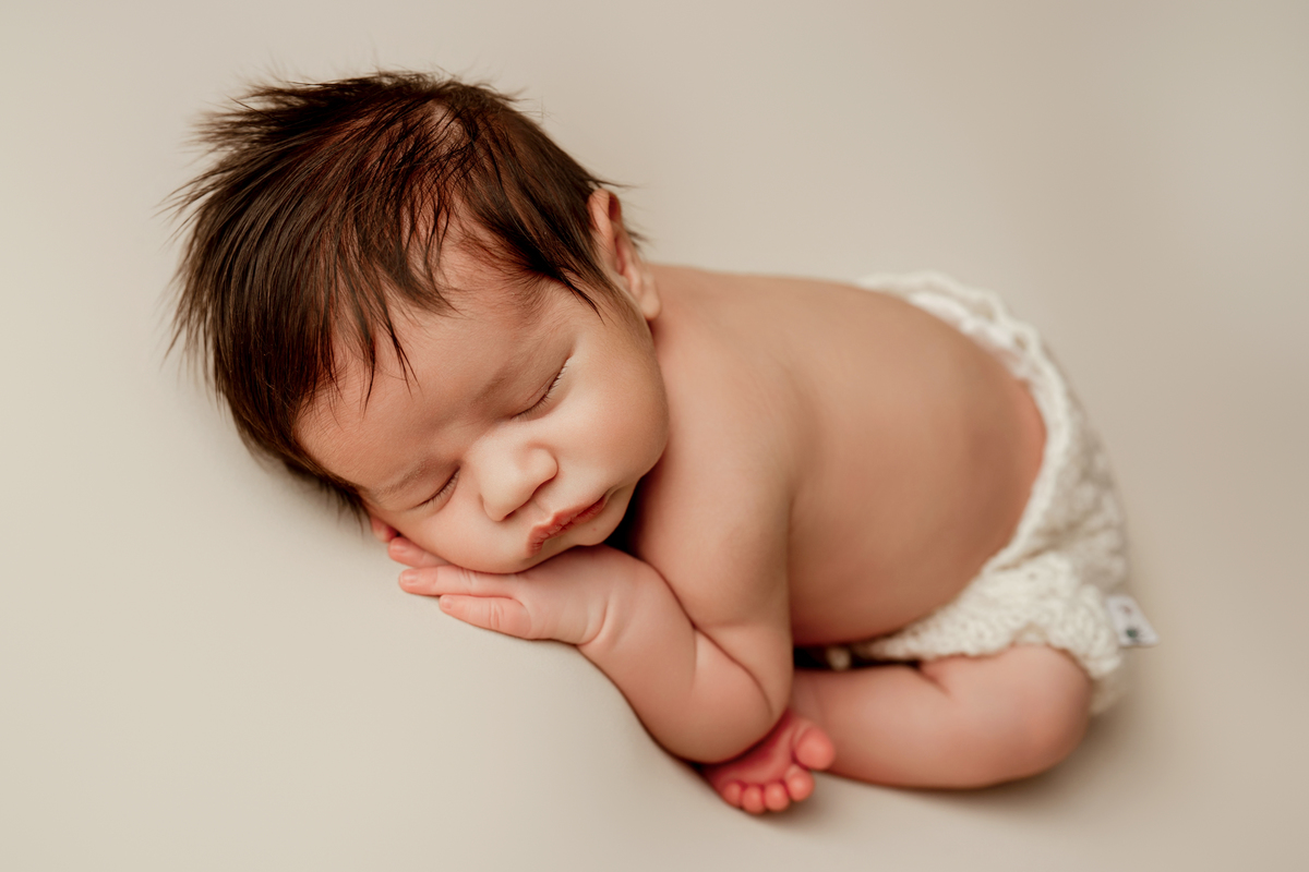 Fotografia newborn de bebé a dormir profundamente. Sessão realizada em ambiente tranquilo e confortável.