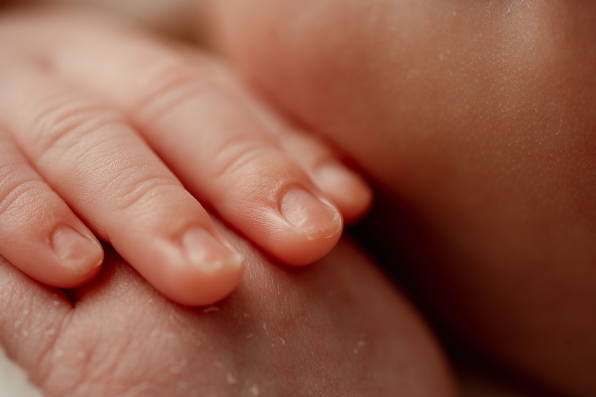 Fotografia macro das mãozinhas de recém-nascida durante sessão newborn profissional.
