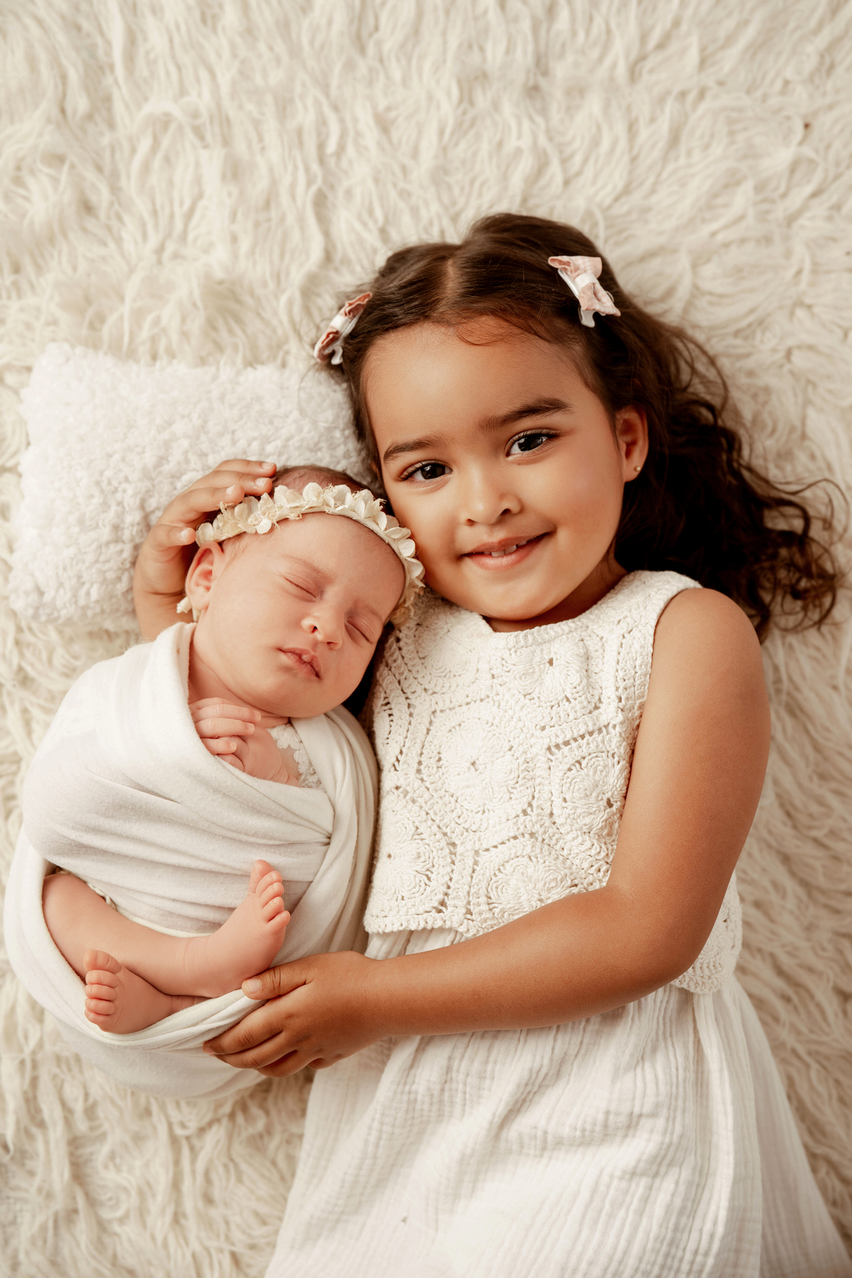 Retrato de família com recém-nascida e irmã mais velha durante sessão newborn em estúdio.
