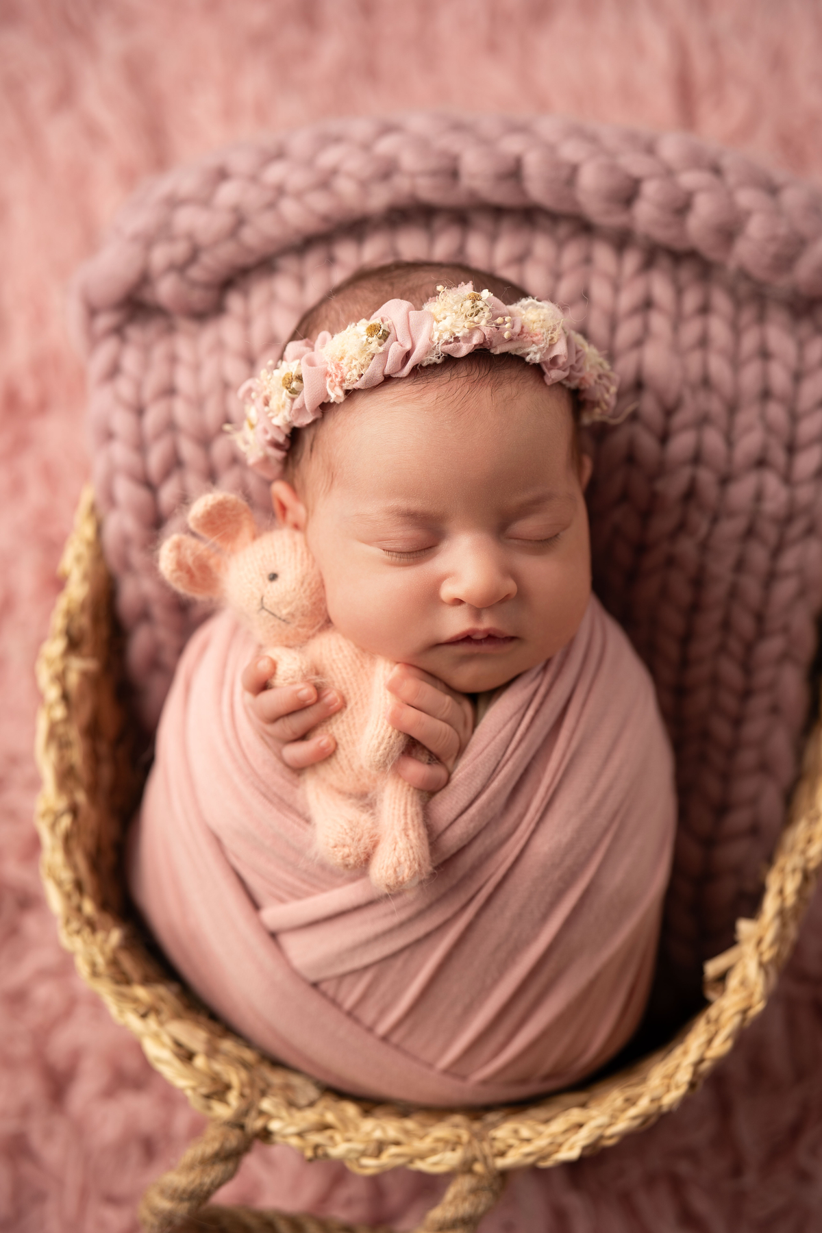 Fotografia newborn de menina embrulhada em tons rosa, realizada por fotógrafa especializada em recém-nascidos em Lisboa.
