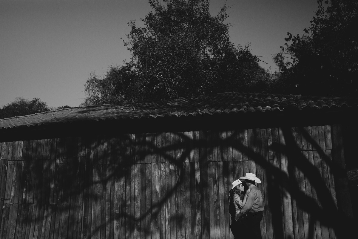 casal namorando ao lado de celeiro em fazenda em valinhos fotografia preto e branco