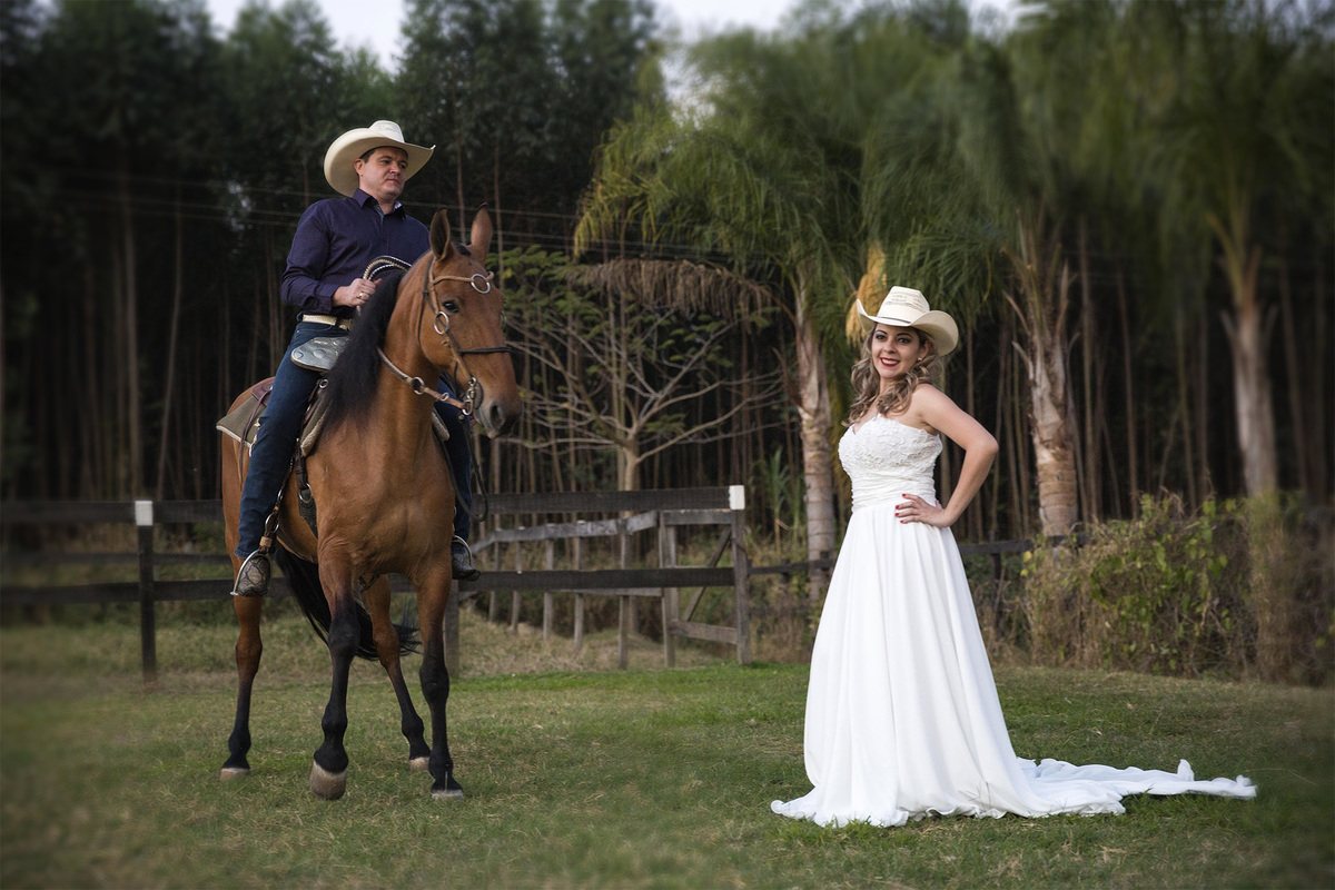 noivo montado a cavalo observa a noiva juliana com vestido em ensaio pré wedding na fazenda