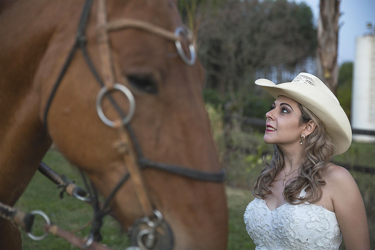 noiva de chapéu observa o cavalo em ensaio na fazenda