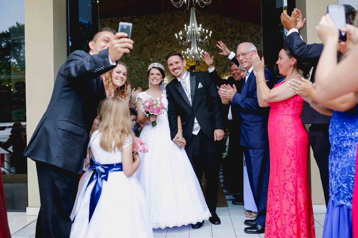 padrinha faz selfie com os noivos em frente a igreja