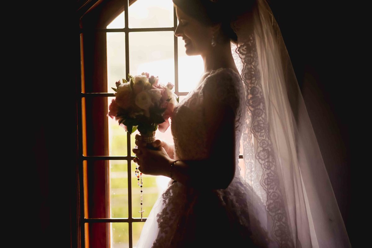 noiva leticia na janela sorrindo com buque