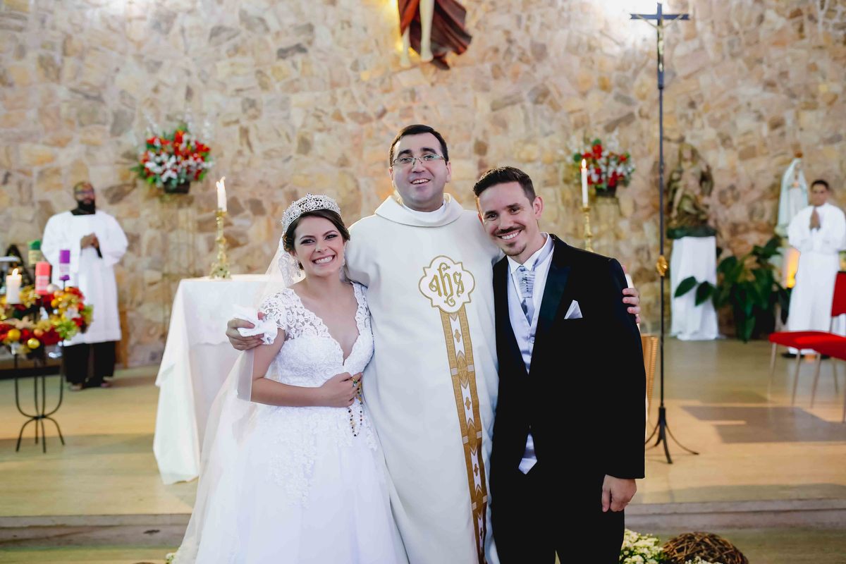 casal de noivos leticia e marcus com padre de cerimonia