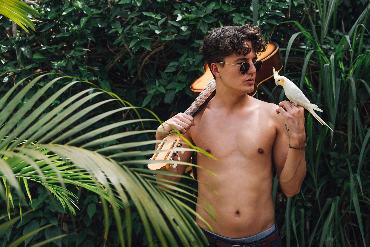 Emil Korkiakoski musico e compositor da banda younghearted em um ensaio em casa em que ele brinca com uma calopsita mansa e segura um violão sobre os ombros