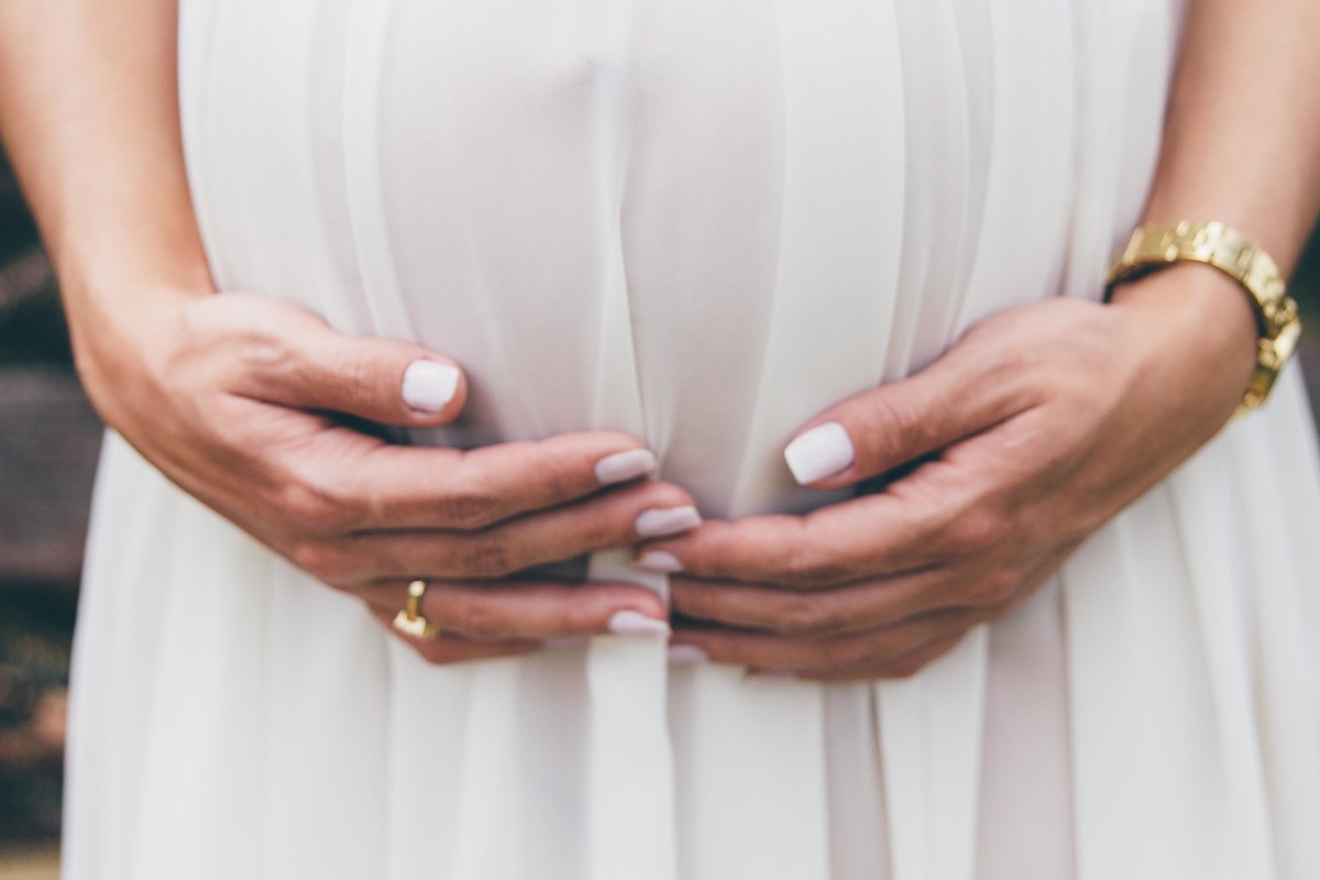 Fotografia de gestante em que a mãe esta segurando a barriga