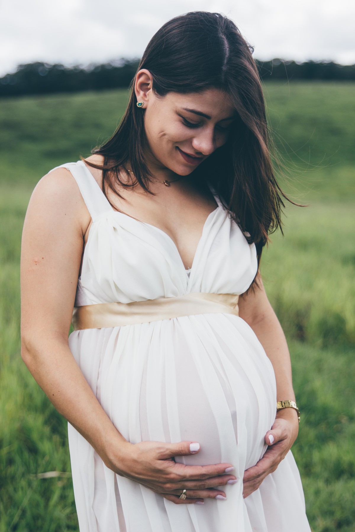 ensaio de gestante em que a mãe esta segurando a barriga e olhando para ela