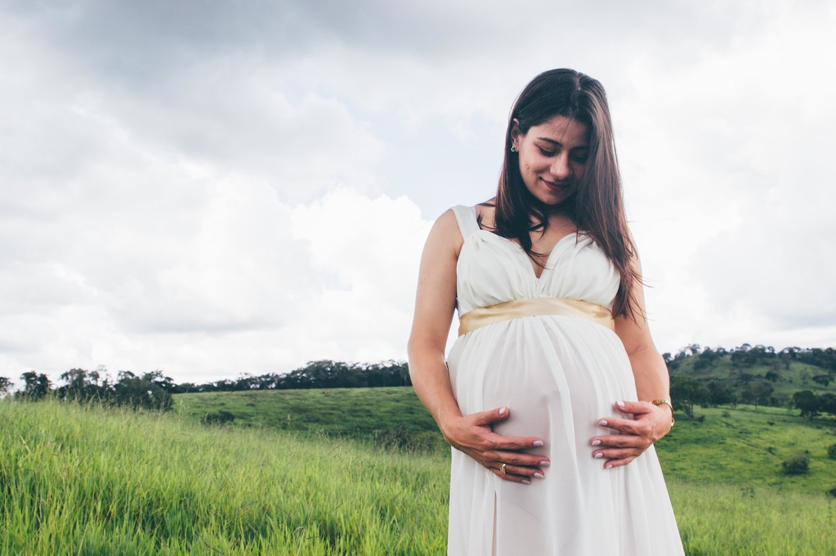ensaio de gestante em que a mãe esta segurando a barriga e olhando para ela