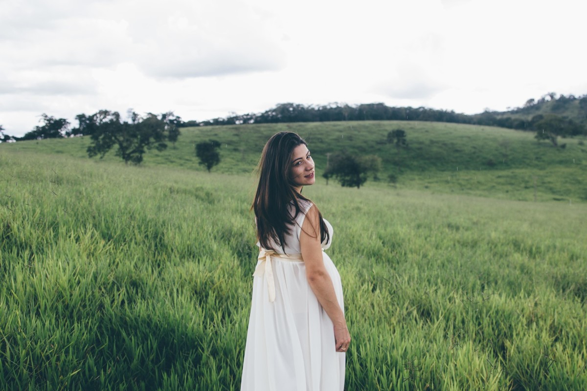 ensaio de gestante em que a grávida esta caminhando pelo bosque e olhando para trás