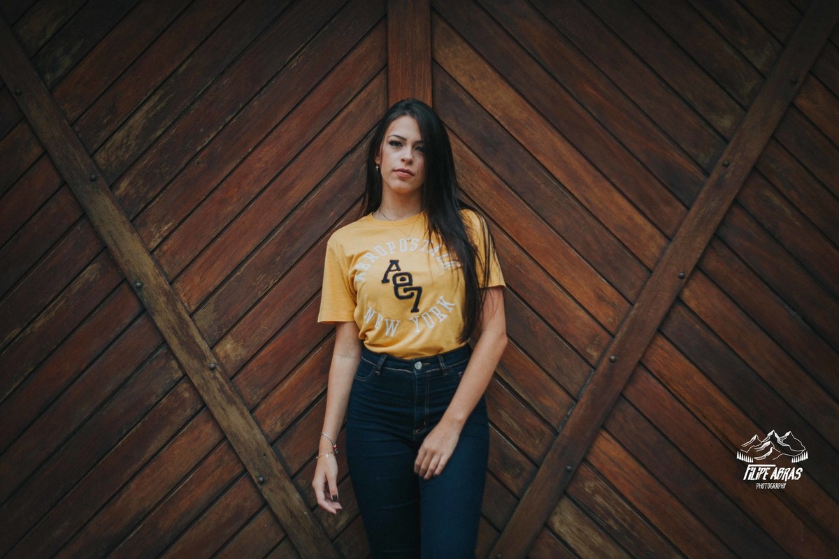 Retrato feminino em que a modelo esta na frente de uma porta de madeira e olhando para o fotografo