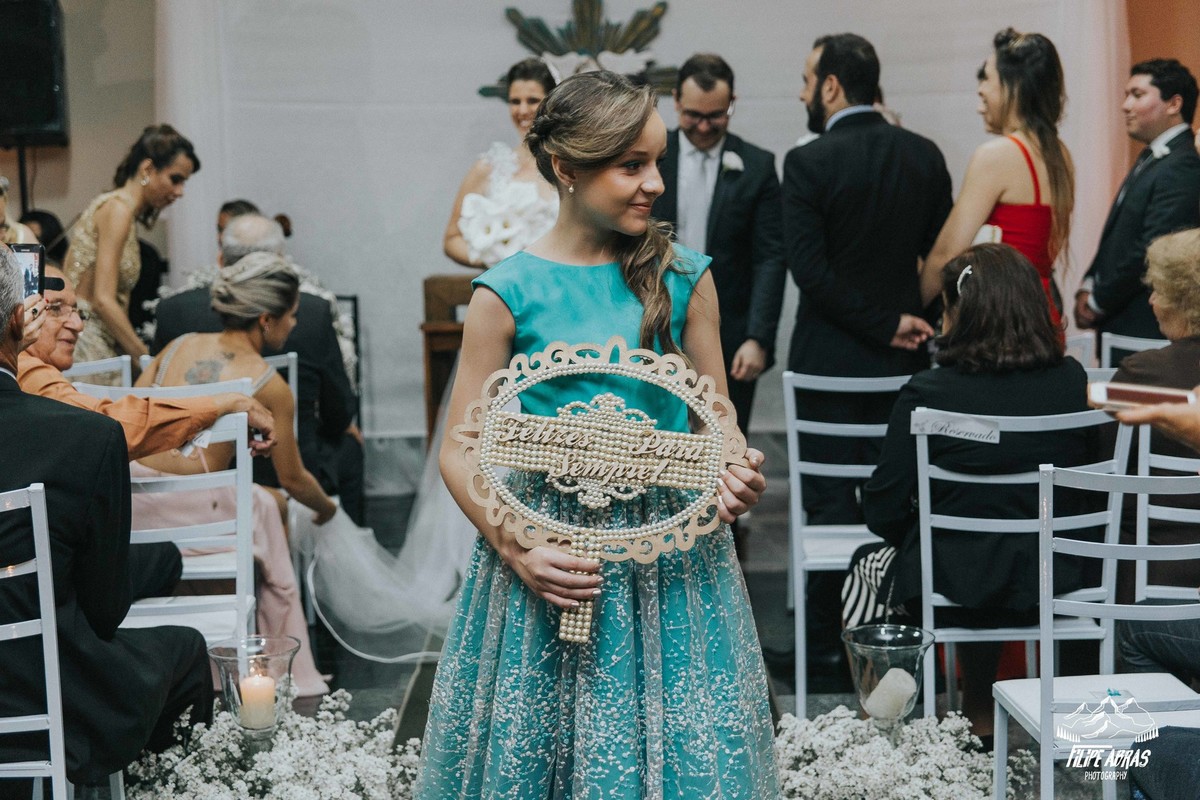 dama de honrra segurando uma plaquinha de saída dos noivos