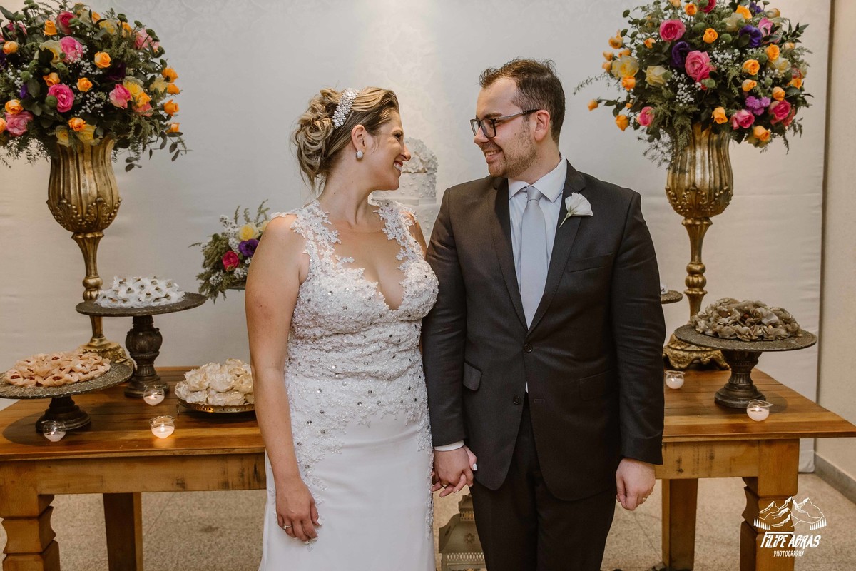 noivos olhando um para o outro na frente da mesa do bolo após casados