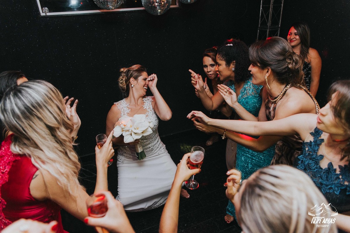 noiva dançando na sua festa de casamento com o buque na mão e madrinhas e convidadas