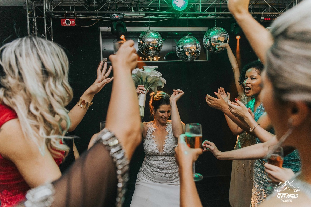 noiva dançando na sua festa de casamento com o buque na mão e madrinhas e convidadas