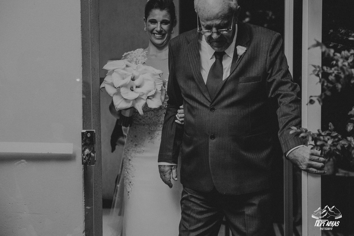 noiva entrando na cerimonia sorrindo e se emocionando