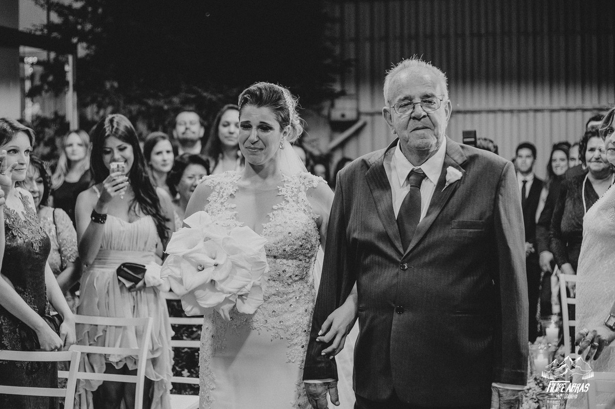 Noiva entrando na cerimonia ao lado do pai emocionada ao ver o noivo