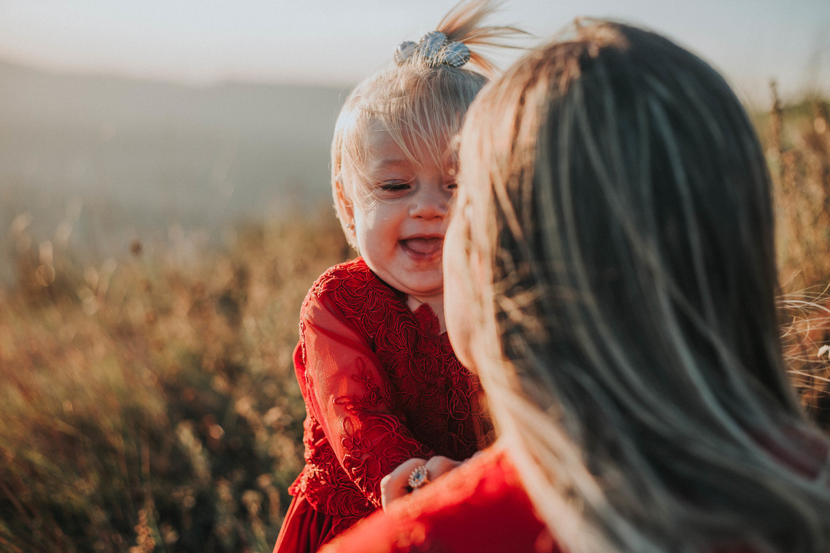 fotografia espontânea de crianças em que a bebe está sorrindo para a mãe
