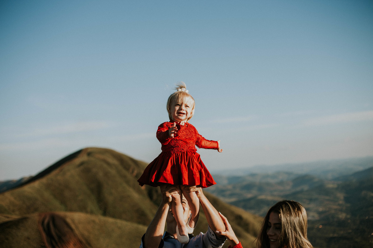 pai levantando a filha no alto durante um ensaio fotografico no topo do mundo minas gerais