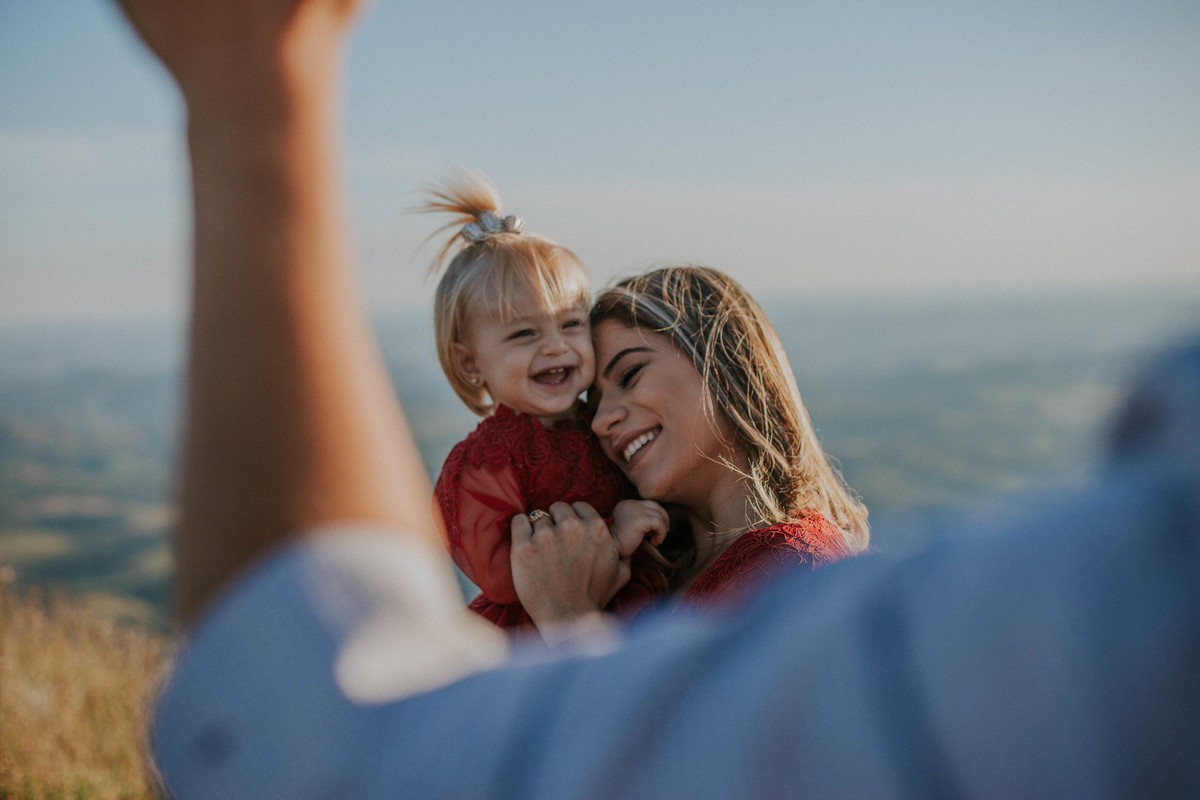 retratos de familia em que a mãe está abraçada com a filha e sorrindo em uma fotografia espontânea