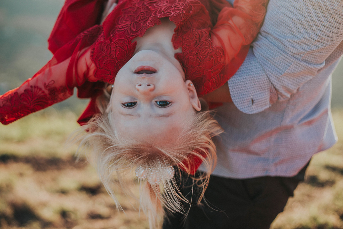 ensaio criativo de familia em que o bebe está de cabeça para baixo e olhando para o fotográfo