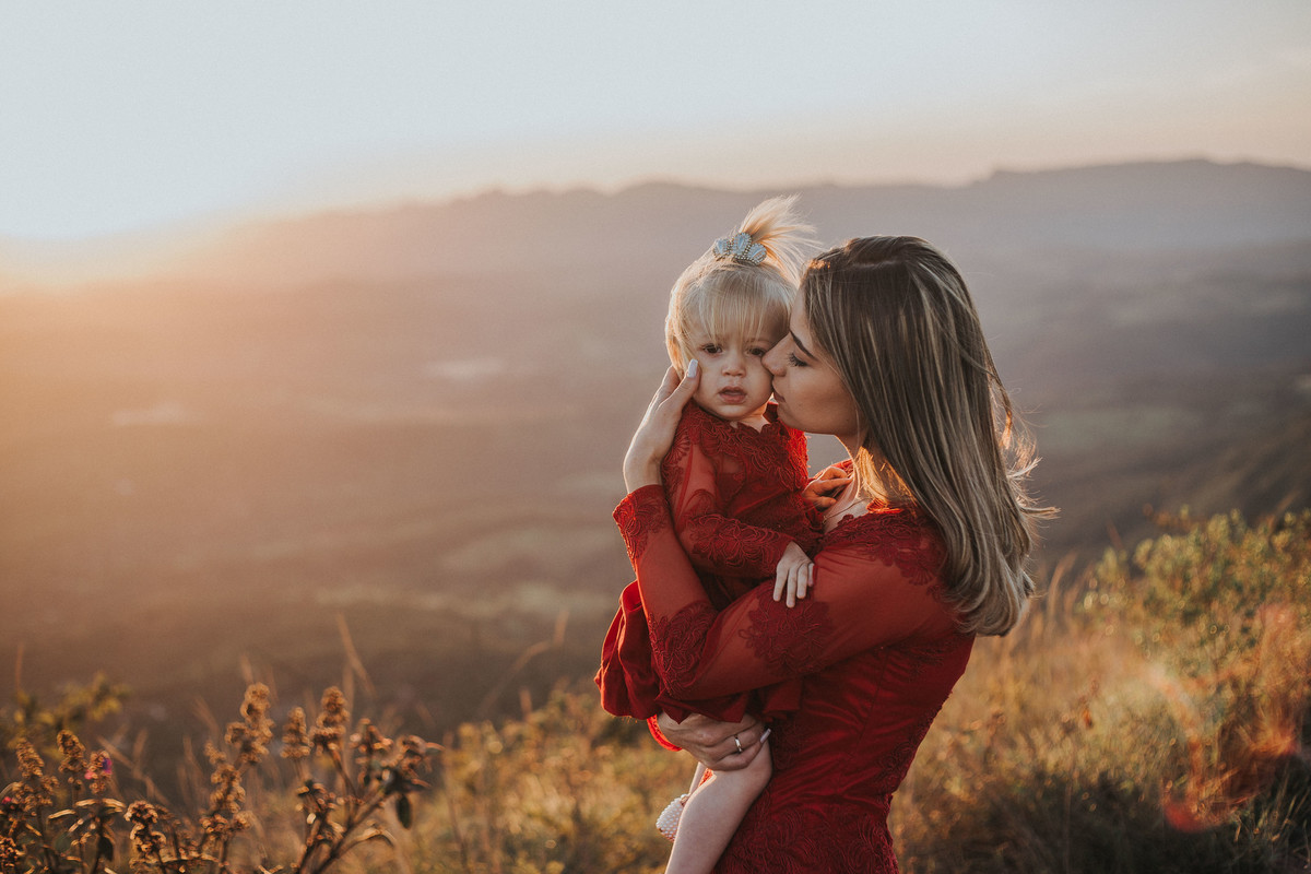 mãe e filha com o mesmo vestido e a mãe está dando um beijo na filha