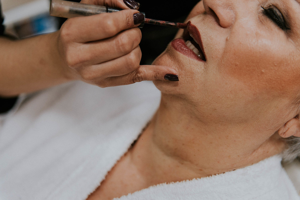 Detalhe do make em que a maqueadora esta passando o baton na mãe da noiva