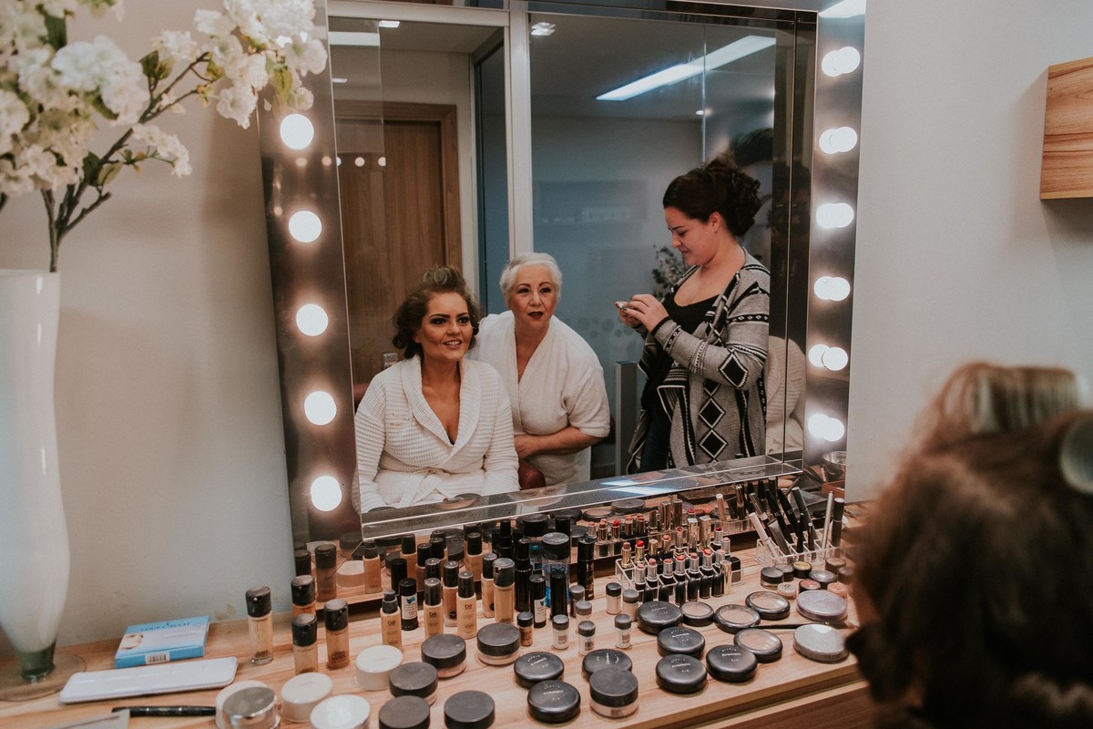 Noiva, mãe da noiva e madrinha no making of olhando os makes