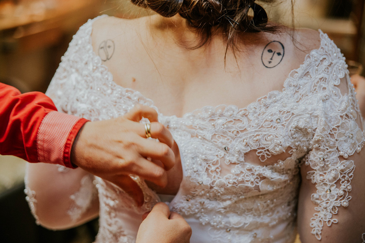 Detalhes da tatuagem da noiva ao fecharem seu vestido