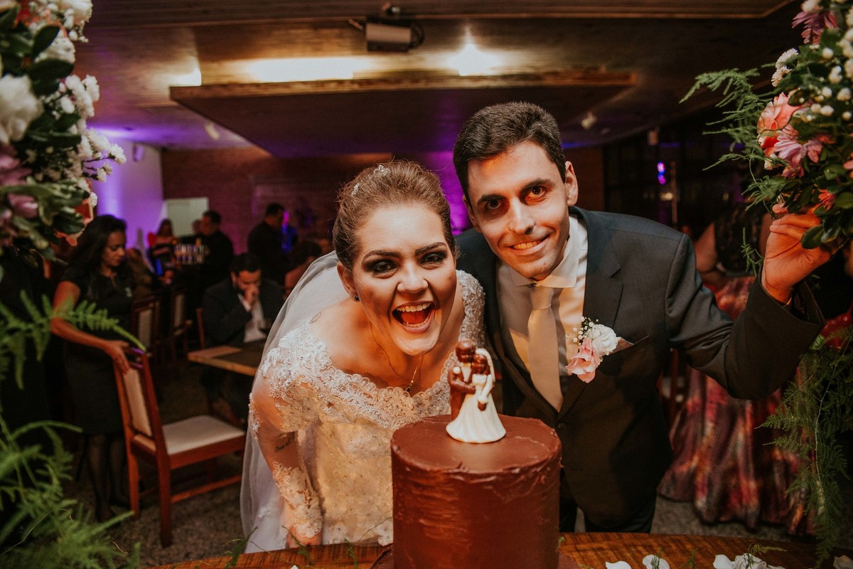 Fotos na mesa do bolo em que os noivos estão zuando