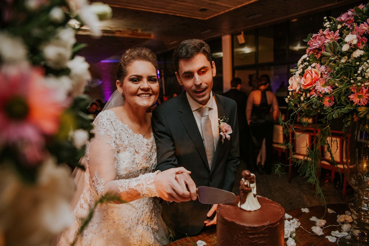 fotografia na mesa do bolo em que os noivos estão cortando o bolo