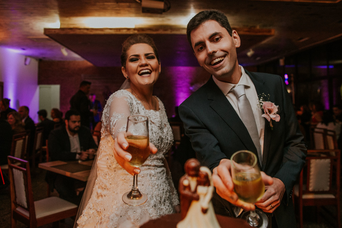 fotografia na mesa do bolo em que os noivos estão dando bebida aos bonecos de topo de bolo de chocolate