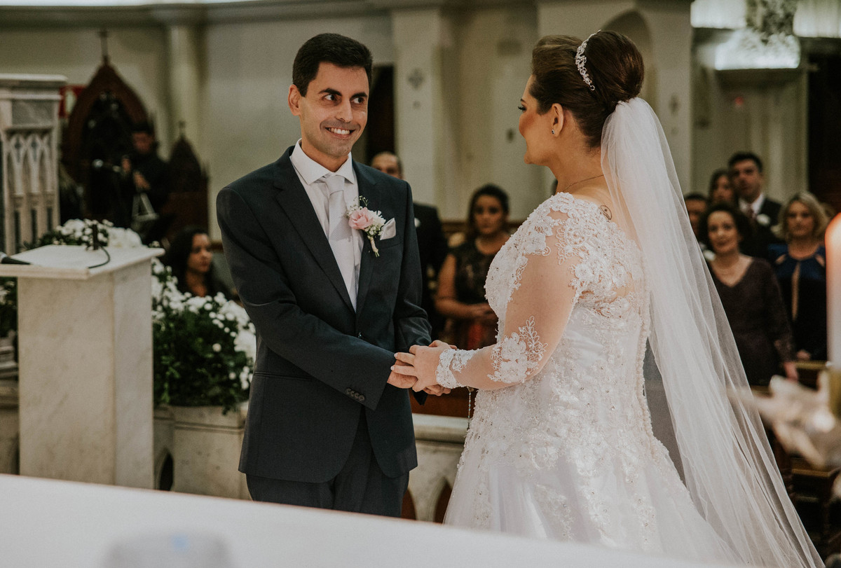 Noivo sorrindo para a noiva ao recebe-la no altar